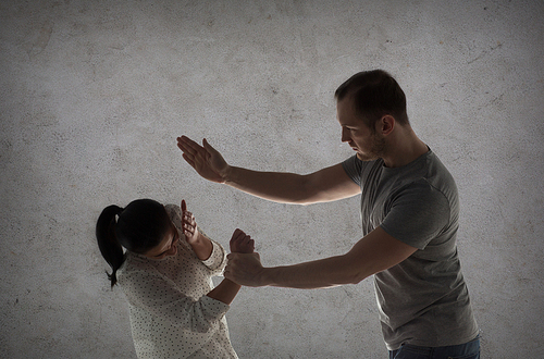 domestic violence, people and abuse concept - couple having fight and man beating woman over gray concrete background