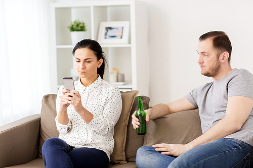 people, relationship difficulties and conflict concept - man drinking beer and woman with smartphone having argument at home