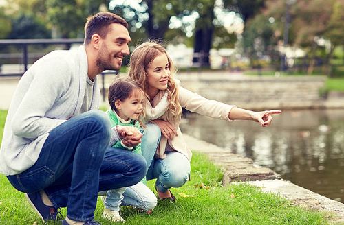 family, parenthood, leisure and people concept - happy mother, father and little girl walking in summer park near pond