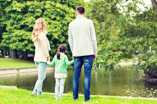 family, parenthood, leisure and people concept - mother, father and little girl walking in summer park near pond