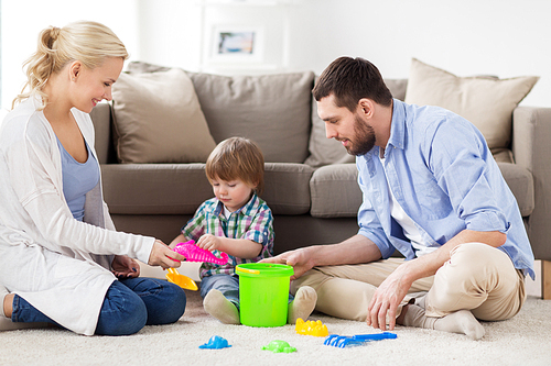 family and people concept - happy little boy and parents playing with beach sand toys set at home