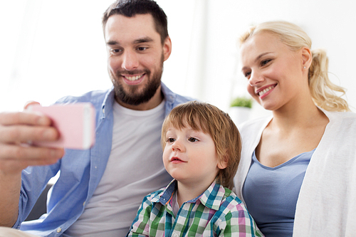 family, technology and people concept - happy mother, father and little boy with smartphone at home