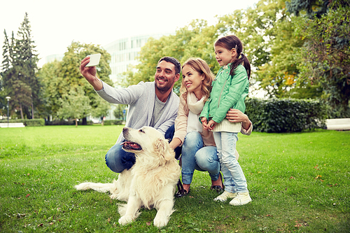 family, pet, animal, technology and people concept - happy family with labrador retriever dog taking selfie by smartphone in park