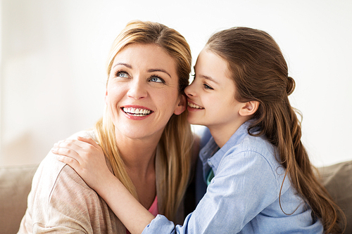 people, trust and family concept - happy daughter whispering secret to her mother at home