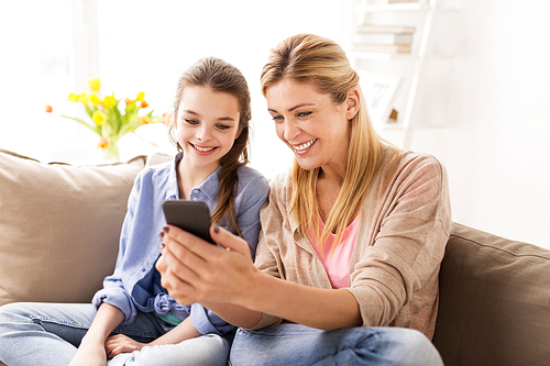 people, family and technology concept - happy girl and mother with smartphone at home
