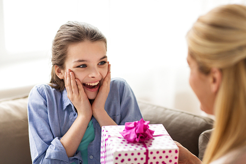 people, holidays and family concept - happy girl receiving birthday present from mother at home
