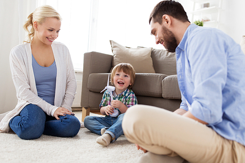 family, renewable energy, ecology and people concept - happy little boy and parents playing with toy wind turbine at home