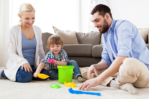 family and people concept - happy little boy and parents playing with beach sand toys set at home