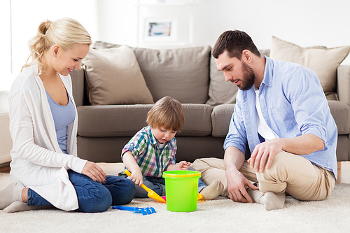 family and people concept - happy little boy and parents playing with beach sand toys set at home