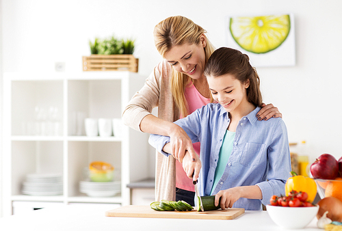 cooking food, healthy eating, family and people concept - happy mother and daughter chopping vegetables for dinner at home kitchen
