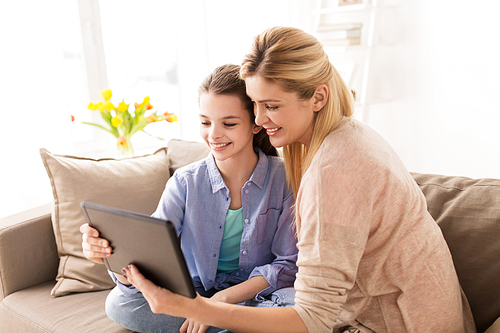 people, family and technology concept - happy girl and mother with tablet pc computer at home