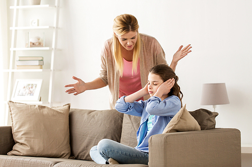 people, conflict and family concept - girl covering ears to not hear angry mother at home