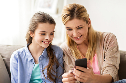people, family and technology concept - happy girl and mother with smartphone at home