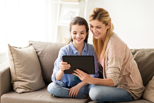 people, family and technology concept - happy girl and mother with tablet pc computer at home