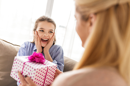 people, holidays and family concept - happy girl receiving birthday present from mother at home