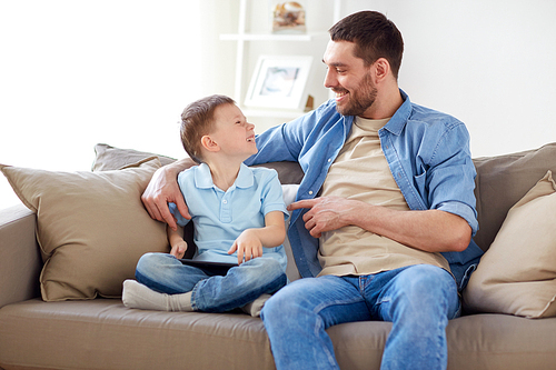 family, fatherhood and people concept - happy father and little son with tablet pc computer sitting on sofa at home