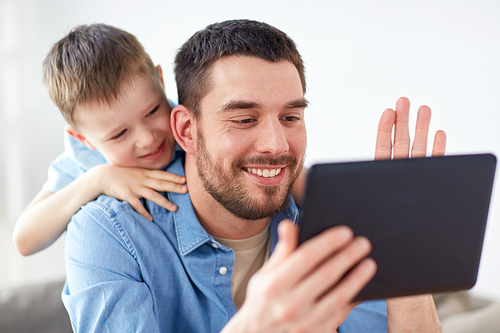 family, technology, communication and people concept - happy father and little son with tablet pc computer having video chat at home