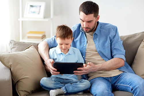 family, fatherhood, technology and people concept - happy father and little son with tablet pc computer sitting on sofa at home