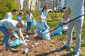 volunteering, charity, people and ecology concept - group of happy volunteers with garbage bags and rake cleaning area in park