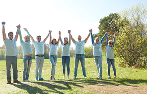 volunteering, charity and people concept - group of happy volunteers holding hands outdoors