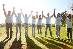 volunteering, charity and people concept - group of happy volunteers holding hands outdoors