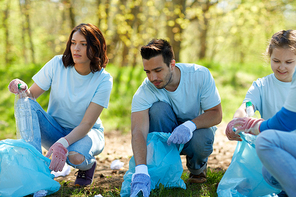 volunteering, charity, people and ecology concept - group of happy volunteers with garbage bags cleaning area in park