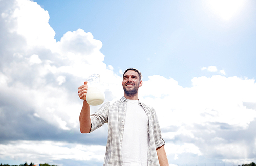 agriculture, farming, people and dairy concept - man or farmer with jug of milk at countryside