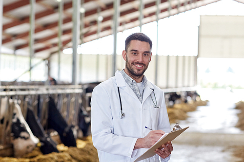 agriculture industry, farming, people and animal husbandry concept - veterinarian or doctor with clipboard and herd of cows in cowshed on dairy farm