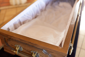 funeral and mourning concept - close up of open empty coffin in church
