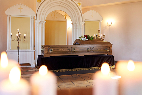 funeral and mourning concept - burning candles and coffin at orthodox church