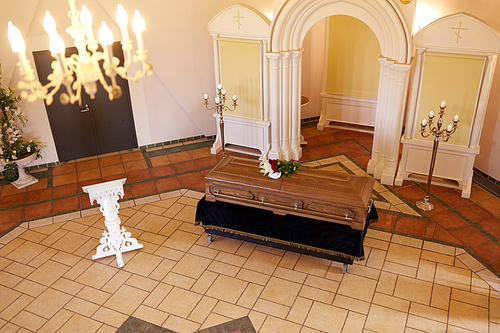 funeral and mourning concept - coffin with flowers and stand in church