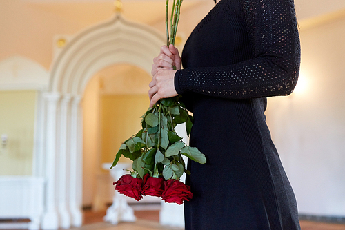 people and mourning concept - woman with red roses at funeral in orthodox church