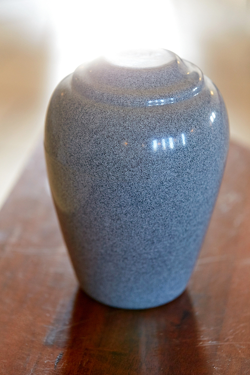 funeral and mourning concept - cremation urn on table