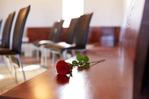 funeral and mourning concept - red roses on bench in church