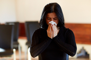 people, grief and mourning concept - crying woman with wipe at funeral in church
