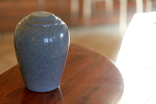funeral and mourning concept - cremation urn on table in church
