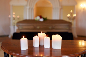 funeral and mourning concept - burning candles and coffin at church