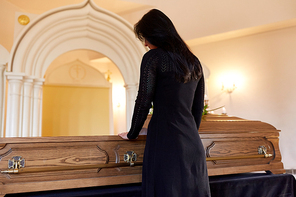 people and mourning concept - sad woman with coffin at funeral in orthodox church