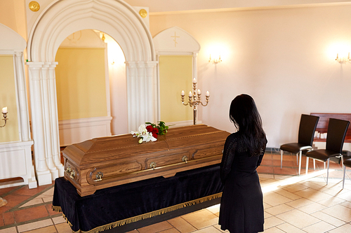 people and mourning concept - sad woman with coffin at funeral in orthodox church