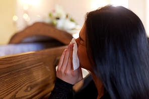 people and mourning concept - crying woman with coffin at funeral in church