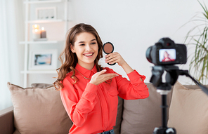 blogging, technology, videoblog, makeup and people concept - happy smiling woman or beauty . with bronzer and camera recording tutorial video at home