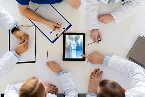 medicine, healthcare and surgery concept - group of doctors or surgeons discussing spine x-ray on tablet pc computer screen at hospital