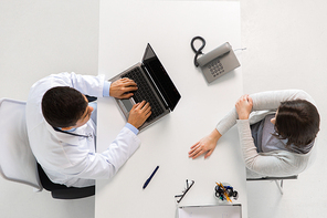 medicine, healthcare and people concept - doctor with laptop computer and young patient woman with injured hand meeting at hospital