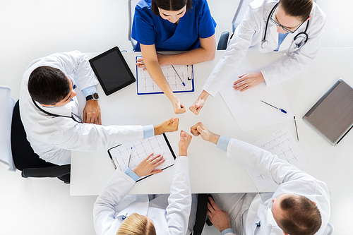 medicine, healthcare and success concept - group of doctors with cardiograms, clipboards and tablet pc computer showing thumbs up over table at hospital