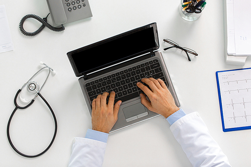 medicine, healthcare and people concept - doctor hands typing on laptop computer sitting at table in clinic