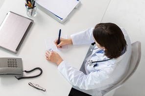 medicine, healthcare and people concept - doctor writing prescription at table
