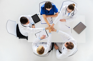 medicine, healthcare and cardiology concept - group of doctors with cardiograms, clipboards and tablet pc computer holding hands together at hospital