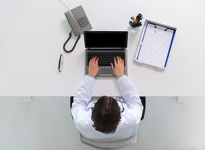 medicine, healthcare and people concept - woman doctor with prescription typing laptop computer sitting at table in clinic