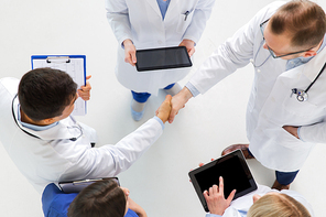 medicine, healthcare and gesture concept - group of doctors with tablet pc computers greeting by handshake at hospital