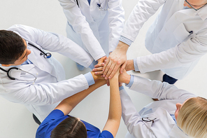 medicine, healthcare, teamwork and people concept - group of happy doctors holding hands together at hospital